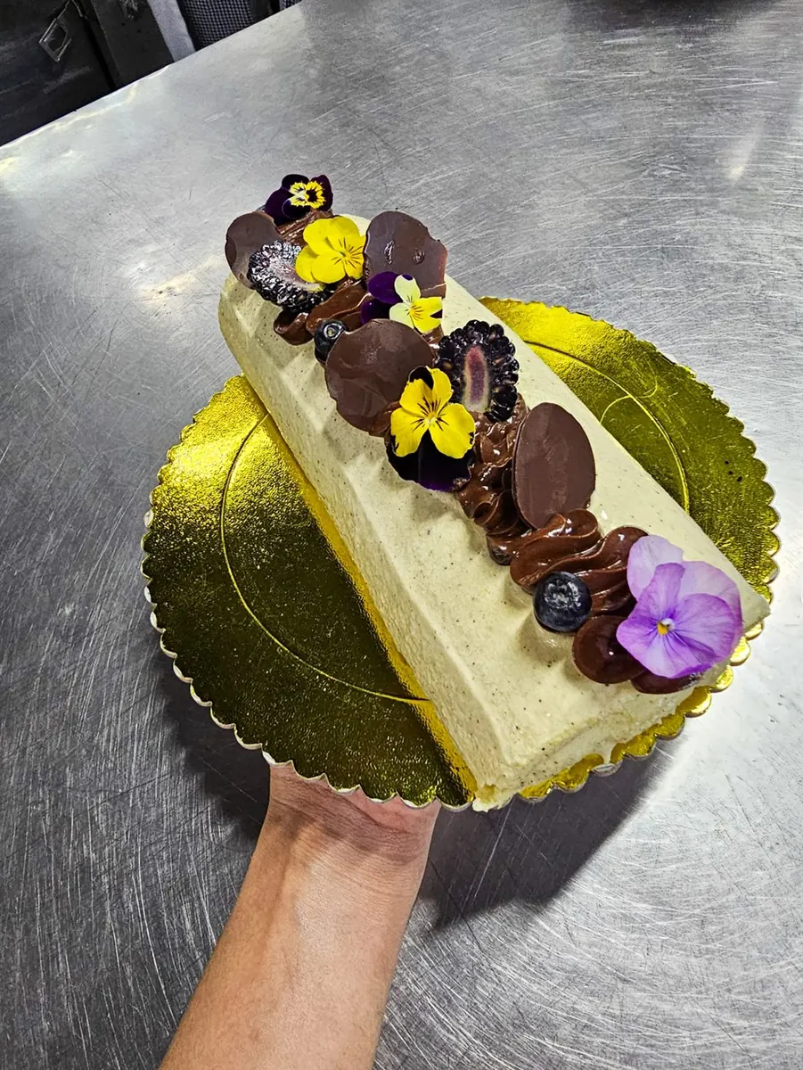 Tronco de torta con crema, chocolate y flores comestibles